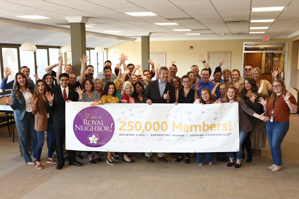 Large group of happy employees behind a 250,000 Members banner.