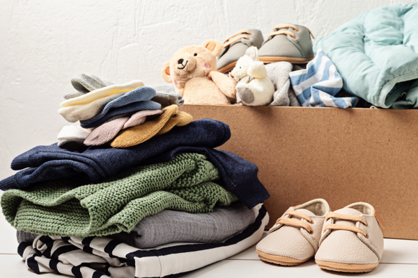 photo of Folded clothing, stuffed animals, and children shoes next to and inside a box.