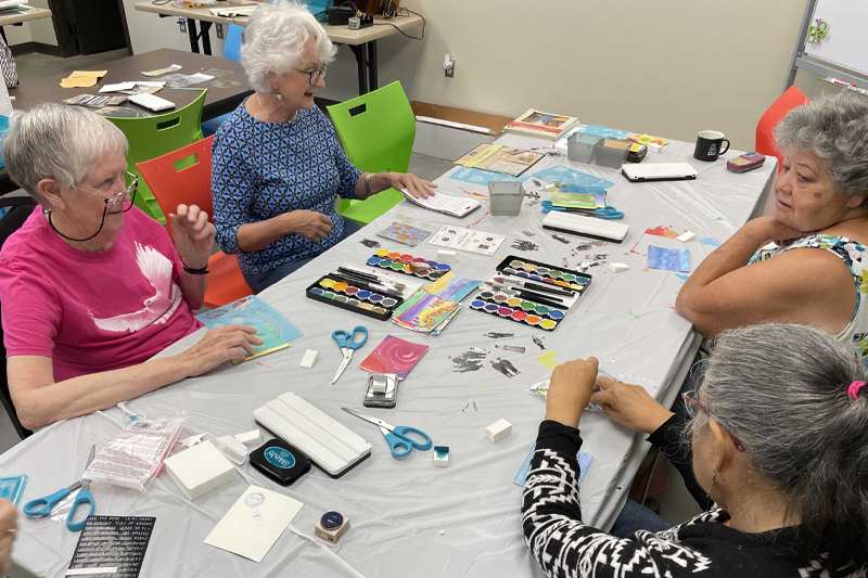photo of Four women sitting at a table crafting cards.