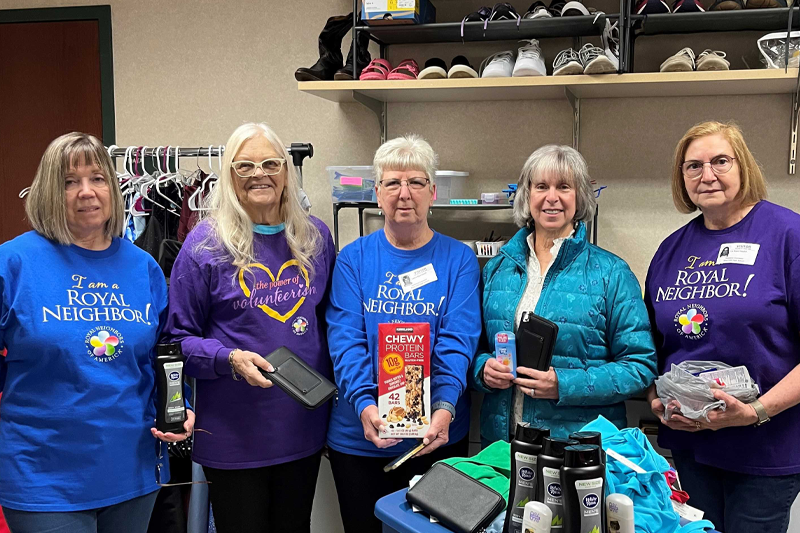 photo of Five happy women holding food and hygeine items in a school's supply closet.