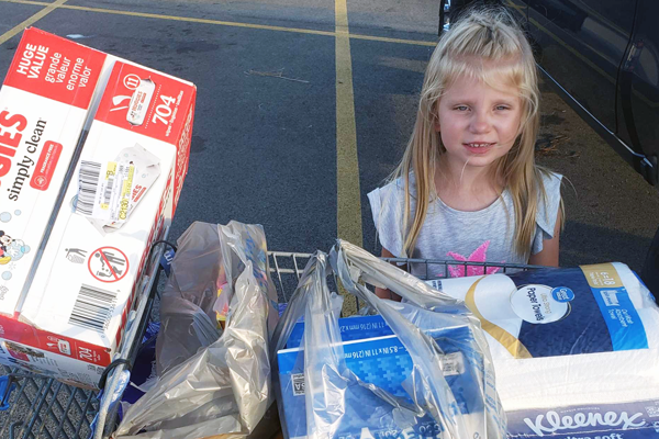 photo of Photo of little blonde girl with grocery cart full of diapers and kleenex.
