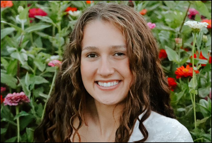 Smiling woman outside in field of flowers.