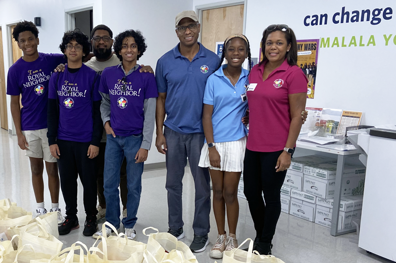 photo of Group of smiling people behind severral tote bags of food.