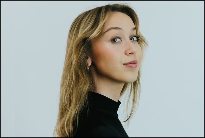 Side view of a smiling blonde woman in a black turtleneck shirt.