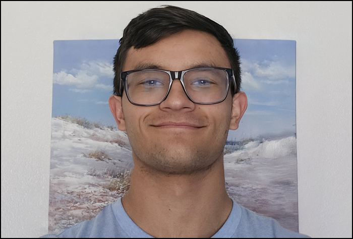Smiling young man with dark hair and glasses.