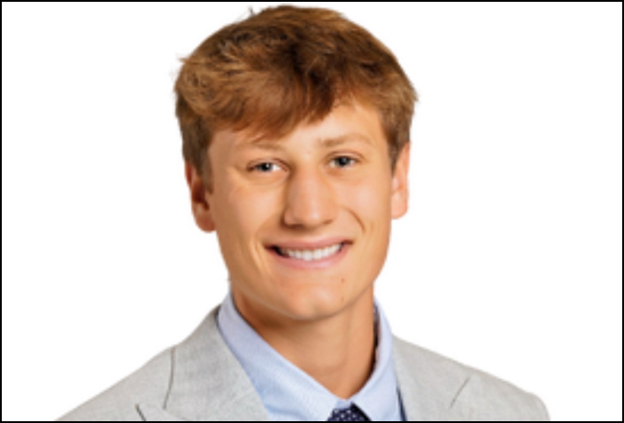 Smiling young man in a gray suite with a white background.