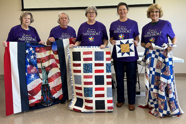 photo of Five happy women holding quilts.