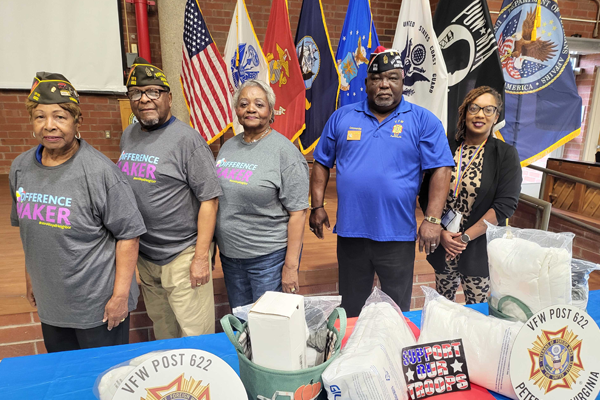 photo of Five people standing in front of flags and begind a table in support of Veterans.